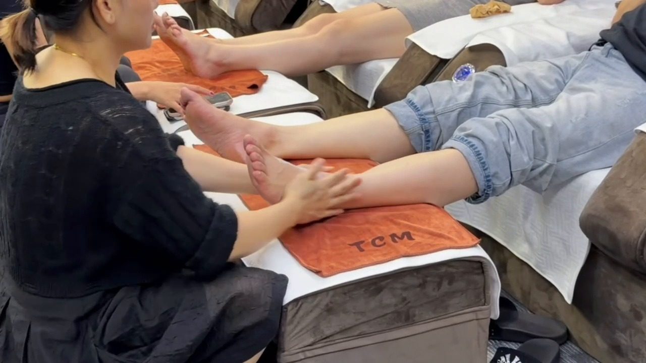 Therapist giving foot reflexology on a towel-covered footrest