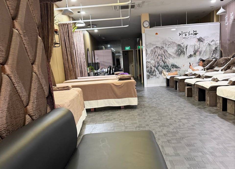 Main hall with massage beds and reflexology chairs under a Chinese landscape mural
